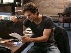 a man sitting at a desk with papers in front of him and an open briefcase on the table