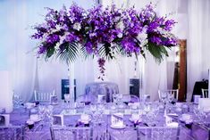 the table is set with purple and white flowers in tall vases on each side