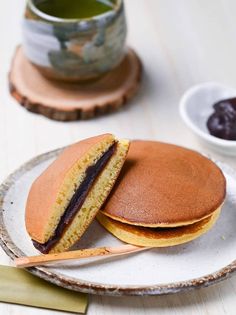 a plate with two cakes on it next to a cup of tea and saucer