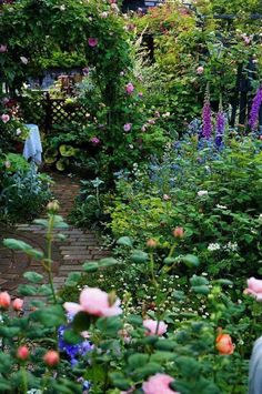 a garden filled with lots of flowers next to a lush green forest covered in pink and blue flowers