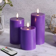 three purple candles sitting next to a remote control