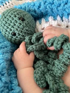 a close up of a baby holding a crocheted octopus toy in their hand