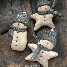 three snowmen with hats and scarfs made out of clay sitting on a wooden surface