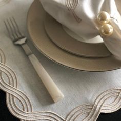 a place setting with silverware, napkins and pearls on the tablecloth is ready to be eaten