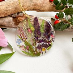 a glass ornament with flowers and leaves in it on a table next to some branches