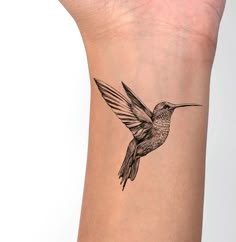 a small hummingbird tattoo on the wrist is shown in black and grey ink,