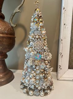 a small christmas tree made out of beads and other items on a table next to a mirror