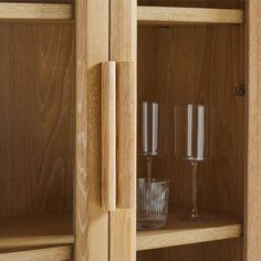 three wine glasses sitting on top of a wooden shelf next to two empty glass goblets