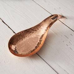 a metal spoon sitting on top of a white wooden floor