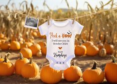 a baby's bodysuit hanging on a clothes line with pumpkins in the background