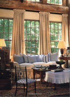 a living room filled with furniture and windows covered in draping next to a rug