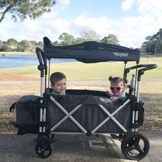 two children sitting in a stroller on the sidewalk