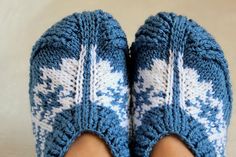 someone's feet wearing blue and white knitted slippers