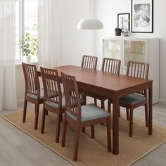 a dining table with six chairs and a rug on the floor in front of it