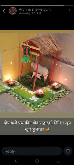 a cow statue sitting on top of a lush green field next to a small hut