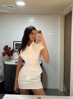 a woman taking a selfie in a white dress