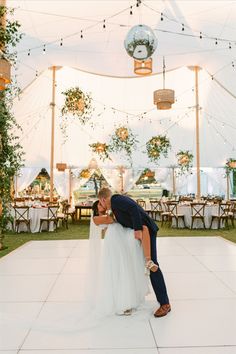 a bride and groom kissing on the dance floor in front of a tented area