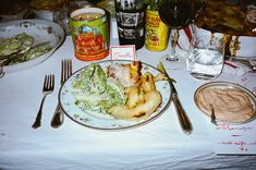 a table topped with lots of food next to wine glasses and plates filled with food