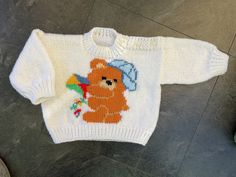 a knitted sweater with a teddy bear on the front and a christmas decoration on the back