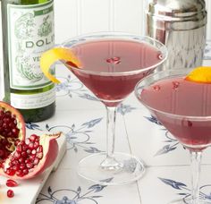 two glasses filled with pomegranate and garnished with an orange slice