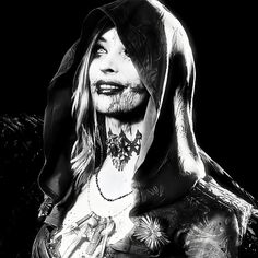 a black and white photo of a woman with tattoos on her face, wearing a hoodie