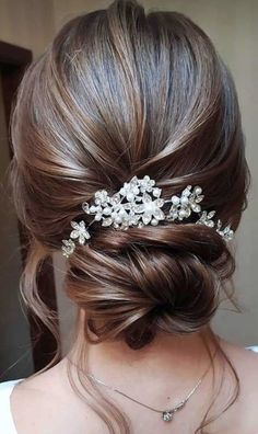 a woman wearing a hair comb with flowers on it's head and her hair pulled back into a low bun