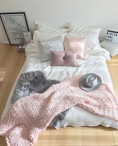 a bed with pillows and blankets on top of it in front of a white wall