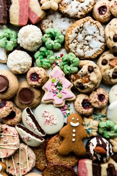 many different types of cookies and pastries on a white table top, with one cookie in the middle