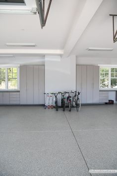 an empty garage with two bikes parked in it and several storage cabinets on the wall