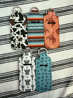 four luggage tags are hanging on a bed with black and white striped sheets in the background