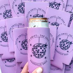 a hand holding a purple can cooler in front of a stack of purple coasters