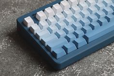 a blue computer keyboard sitting on top of a gray floor next to a black mouse