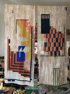 two quilts hanging on the wall next to each other in a room filled with clutter