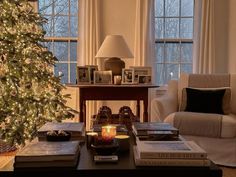 a living room filled with furniture and a christmas tree in front of two large windows