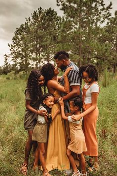 a group of people that are standing in the grass with their arms around each other