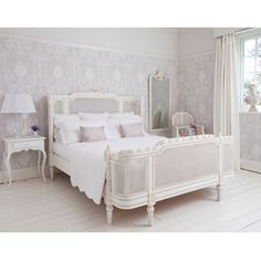 a white bed sitting in a bedroom next to a window