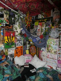 a bed covered in lots of assorted items and posters hanging on the wall above it