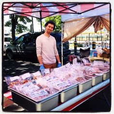 a man standing in front of a table with food on it and bags behind him