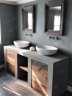 two white sinks sitting on top of a wooden counter in a bathroom next to mirrors