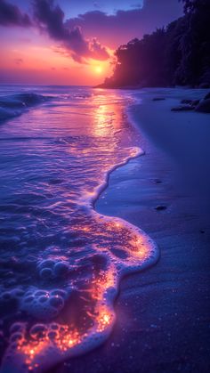 the sun is setting over the ocean and it's reflection in the water on the beach