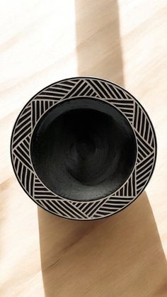 a black and white bowl sitting on top of a wooden table