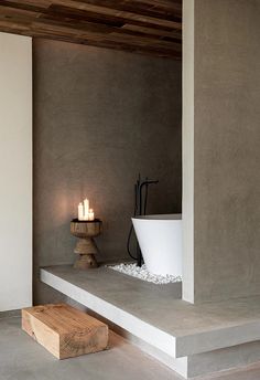 a bathroom with concrete walls and flooring next to a bathtub filled with candles