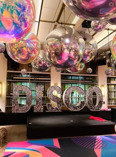 balloons are floating in the air above a sign that says disco on it's side