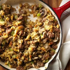 a skillet filled with stuffing on top of a wooden table