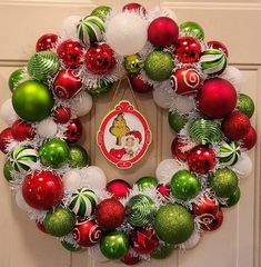 a christmas wreath is hanging on the front door with ornaments around it and an ornament