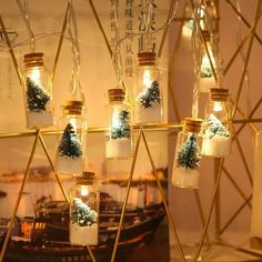 christmas lights in glass jars are hanging from a wire with snow and pine trees inside