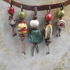 a group of different colored beads hanging from a leather cord on top of a stone wall