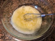 a glass bowl filled with batter on top of a granite counter next to a metal whisk