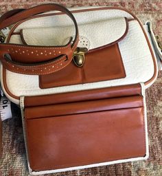 This elegant shoulder bag is very versatile: for business, travel, and daily use- it fits all the purposes. It has an integrated brown documents/money holder, and has multiple compartments and pockets: Exterior- one open, one buckled, one zipped compartment. Interior- 2 compartments for cards, 3 pockets, and 3 compartments in the integrated wallet. Measurements: Height of the bag- 7" Width- 9" Depth- 3" The width of the integrated docs/money folder- is 6 ½" Adjustable strap- 15"-18" The bag is not lined. Decorated with tassels and perforated light color leather, from under which cinnamon-brown leather is visible. It is a product of the 80s, but it is in excellent condition (please look at the photos). This leather is weather-resistant. Brown Travel Satchel With Cell Phone Pocket, Brown Wallets For Everyday Use, Classic Shoulder Bag With Interior Card Slots For Travel, Formal Brown Shoulder Bag With Cell Phone Pocket, Vintage Bags With Interior Card Slots For Everyday, Vintage Travel Bag With Cell Phone Pocket, Classic Travel Shoulder Bag With Cell Phone Pocket, Classic Shoulder Bag With Cell Phone Pocket For Travel, Classic White Wallet For Travel