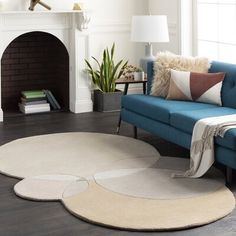 a living room with a blue couch and white rugs on the hardwood flooring